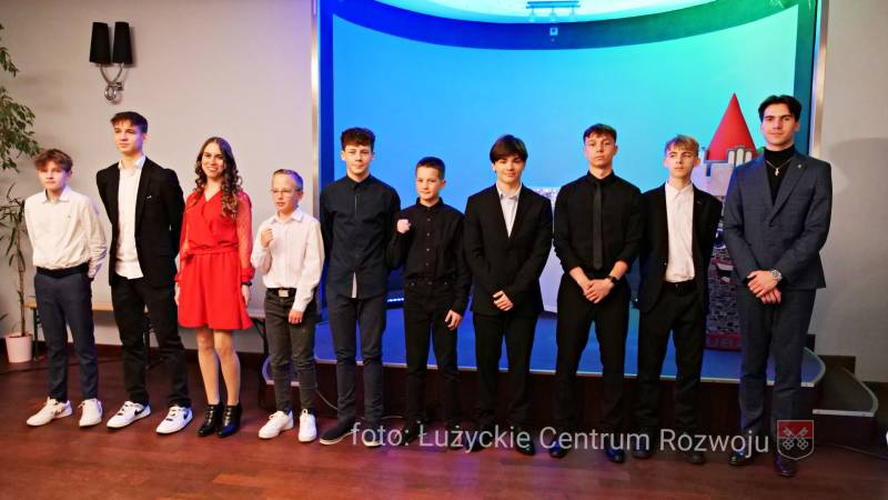 9 zawodników i 1 zawodniczka stoją w rzędzie obok siebie